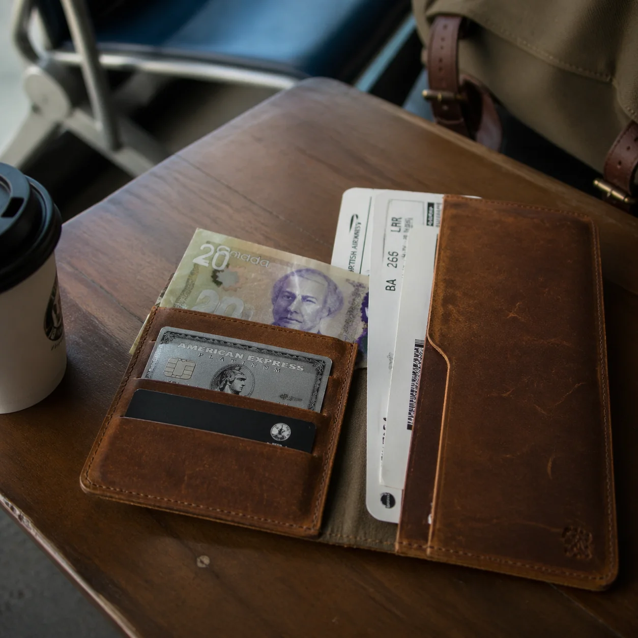 Leather travel wallet with a metal rewards credit card and boarding pass on an airport lounge table